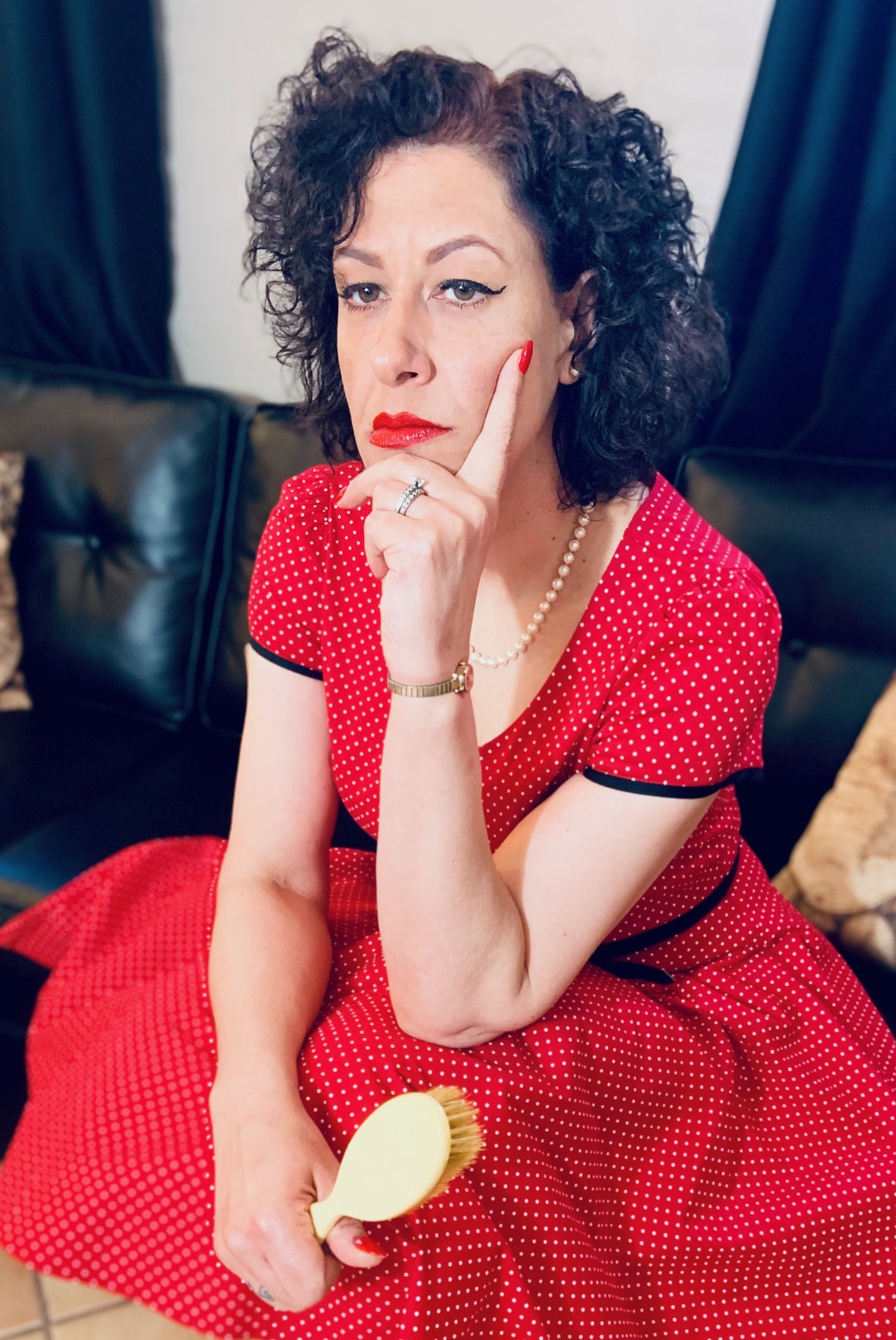 Miss Chris in a red dress with a hairbrush pondering your punishment