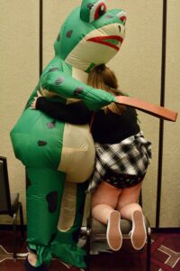 Nemo dressed as a Frog spanking a schoolgirl with a strap.